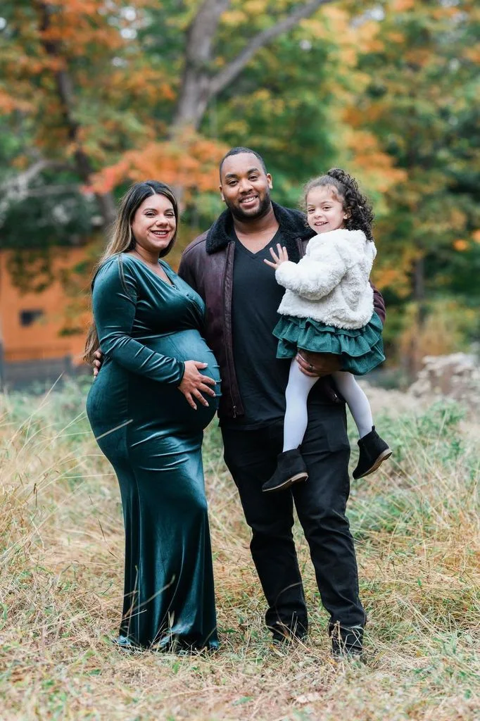 Family photo of a pregnant mom, dad, and daughter 