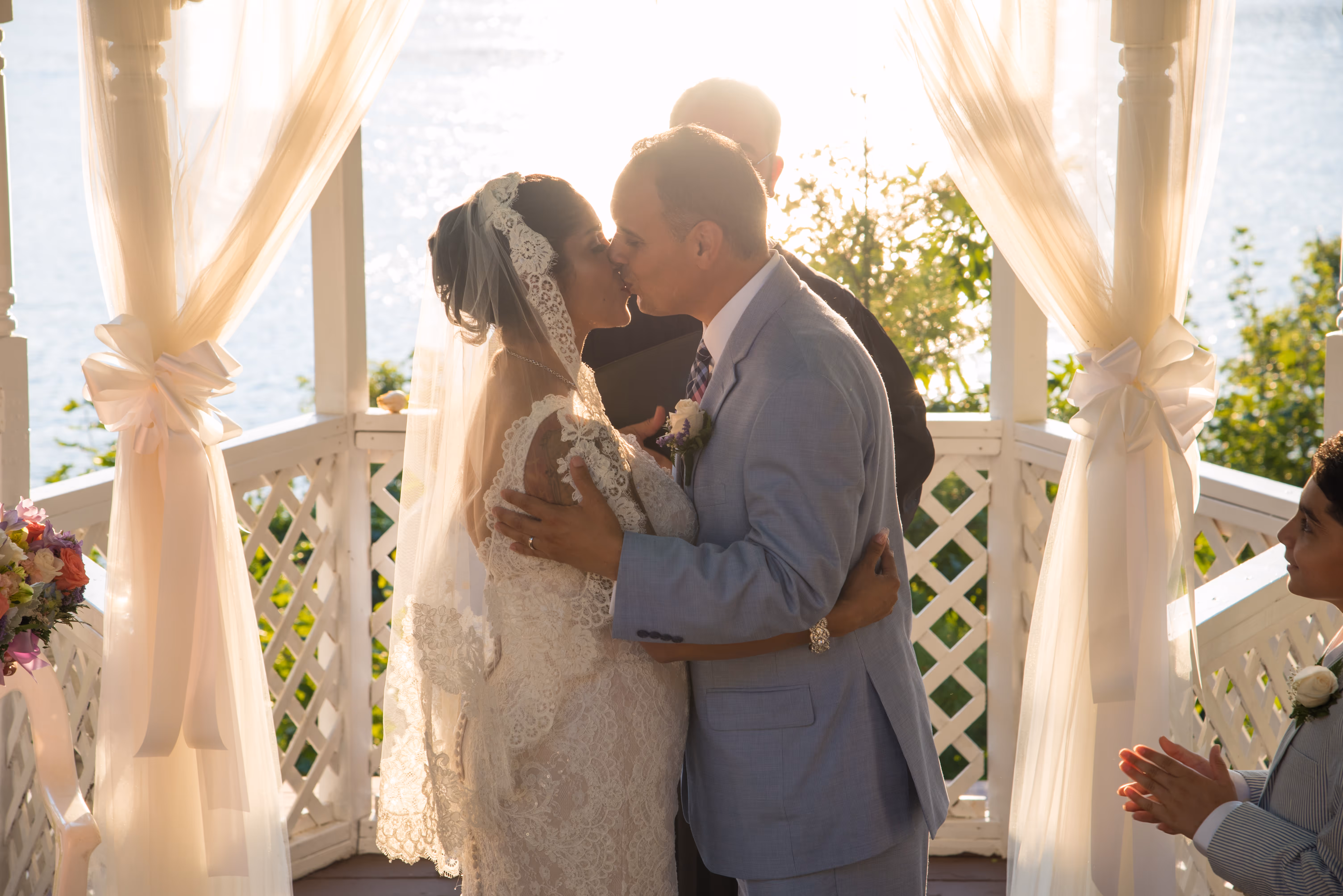 A bride and groom kissing on a porch.