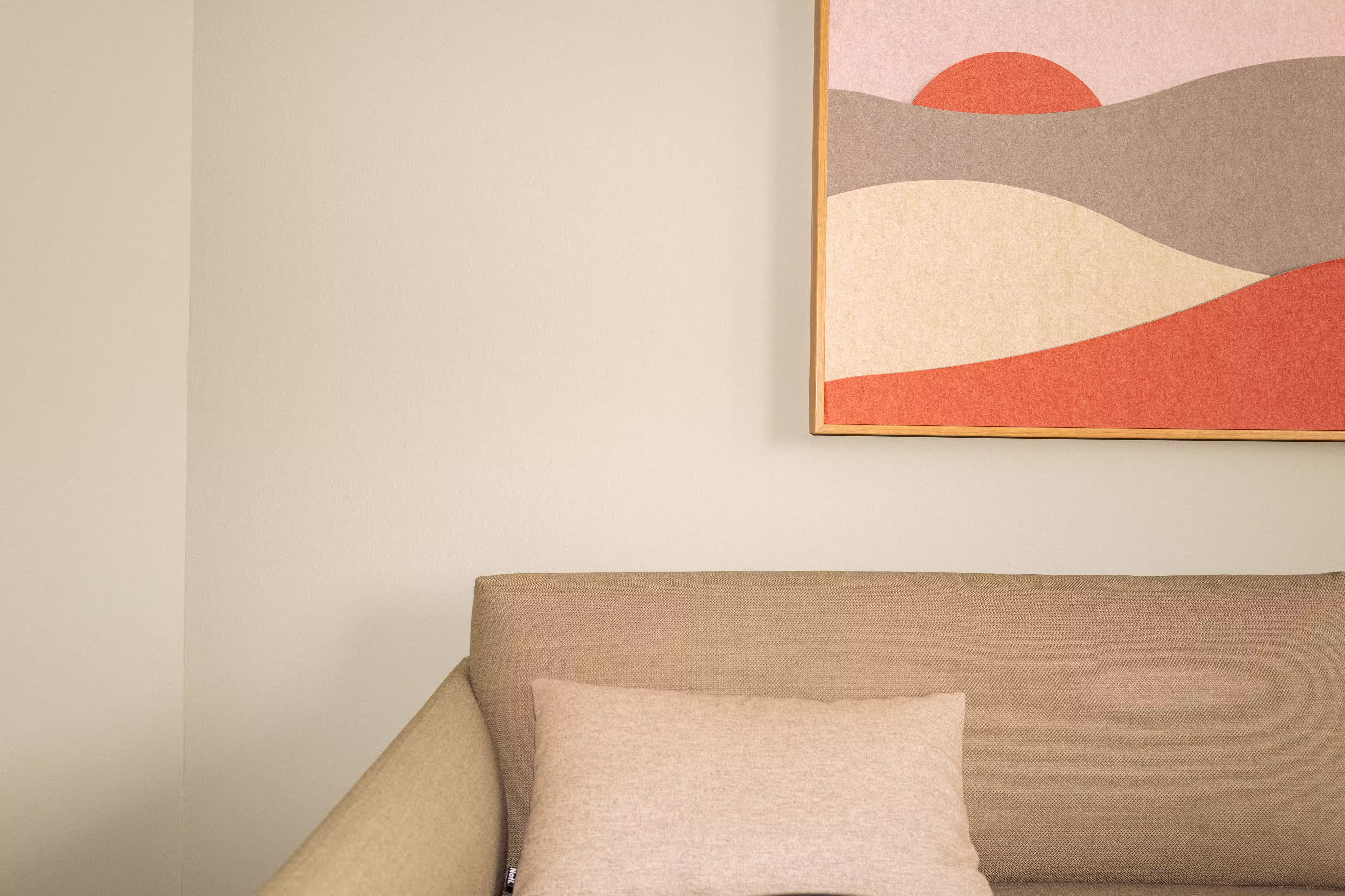 Impression eines Therapieraum bei klein&groß mit einem grünen Sofa und einem Akkustikbild an der Wand