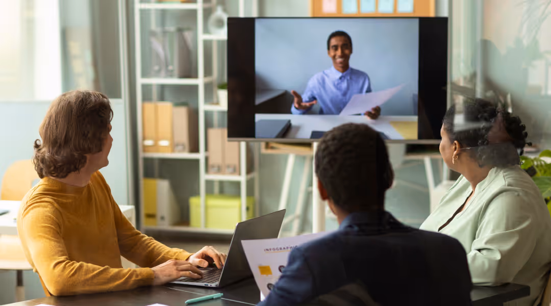 A group of colleagues having a meeting with someone online