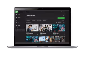 Laptop showing a video overview dashboard interface with video thumbnails and navigation menu.