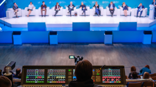Camera and audio mixing desk filming a panel discussion with eleven speakers on a conference stage
