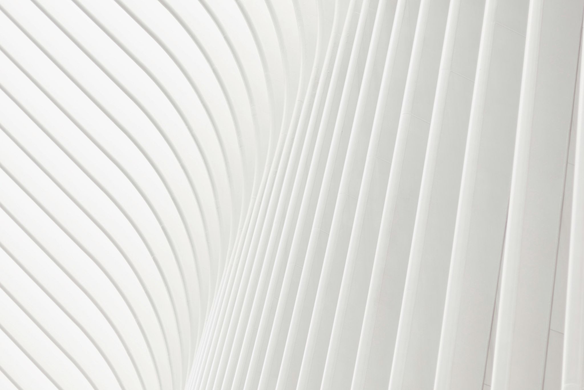 Abstract white architectural structure with curved and parallel vertical lines.