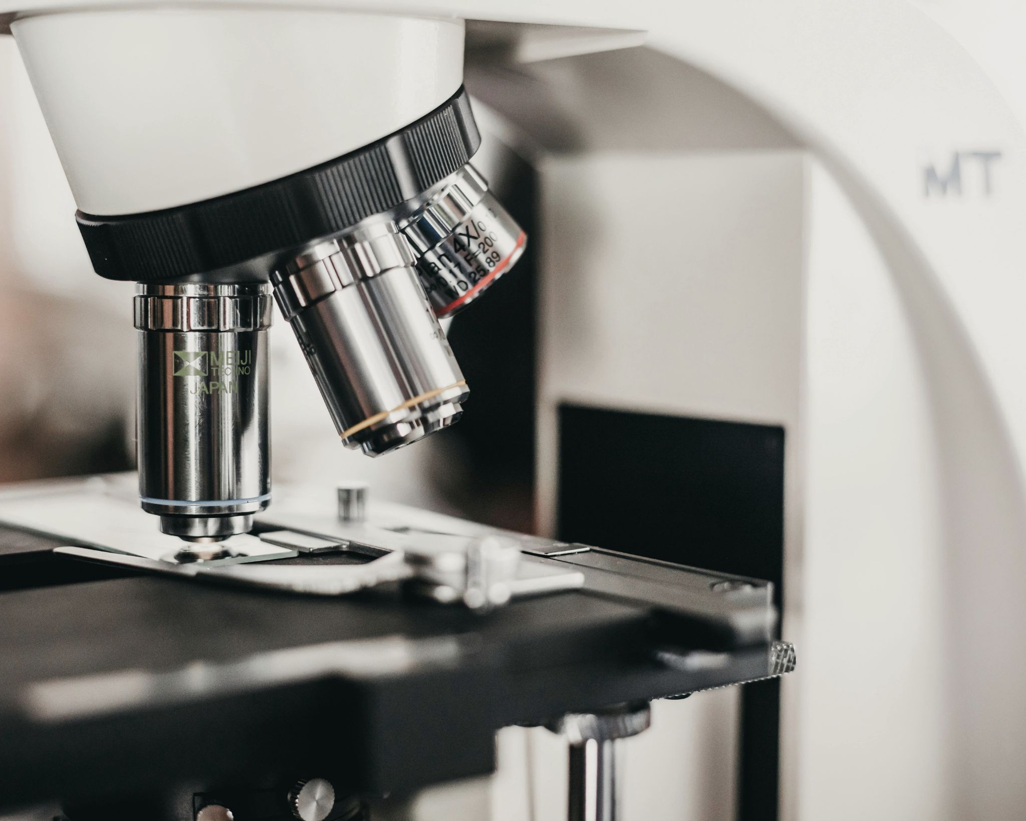 Close-up of a laboratory microscope focusing on its objective lenses and slide holder.