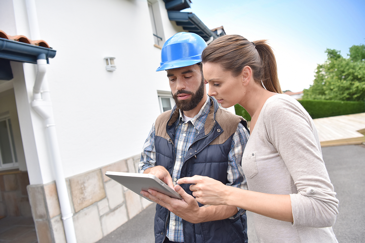 Construction workers reviewing plans on tablet outside building site