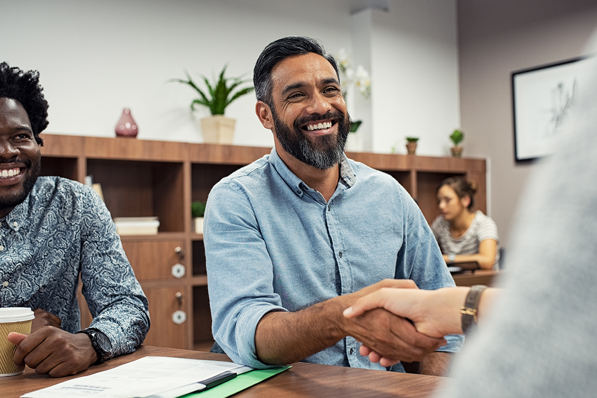 Smiling businessmen shaking hands in a modern office workspace