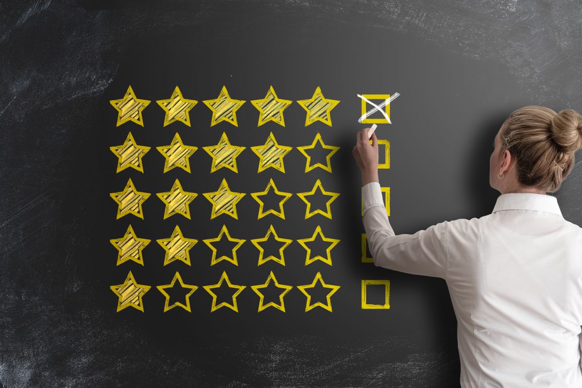 Person drawing stars on chalkboard representing ratings or performance evaluation