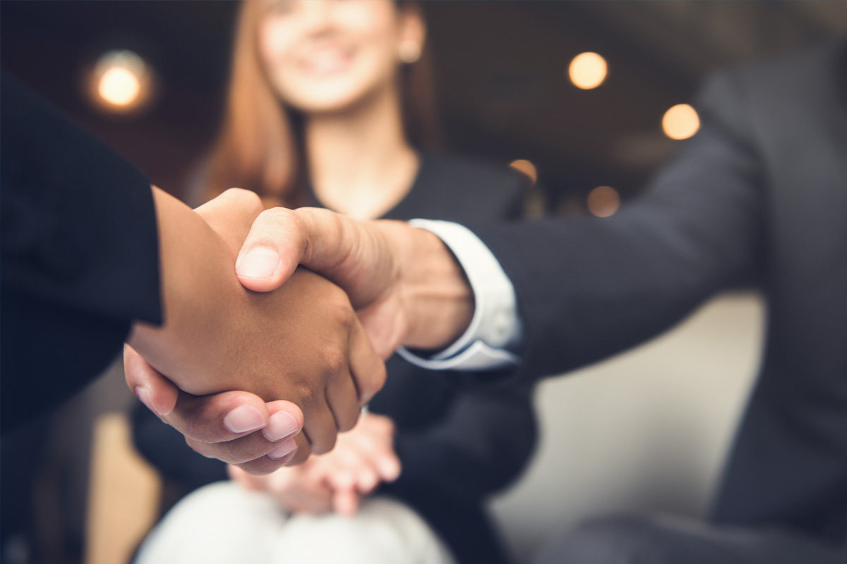 Business professionals shaking hands in a warm, blurred office setting