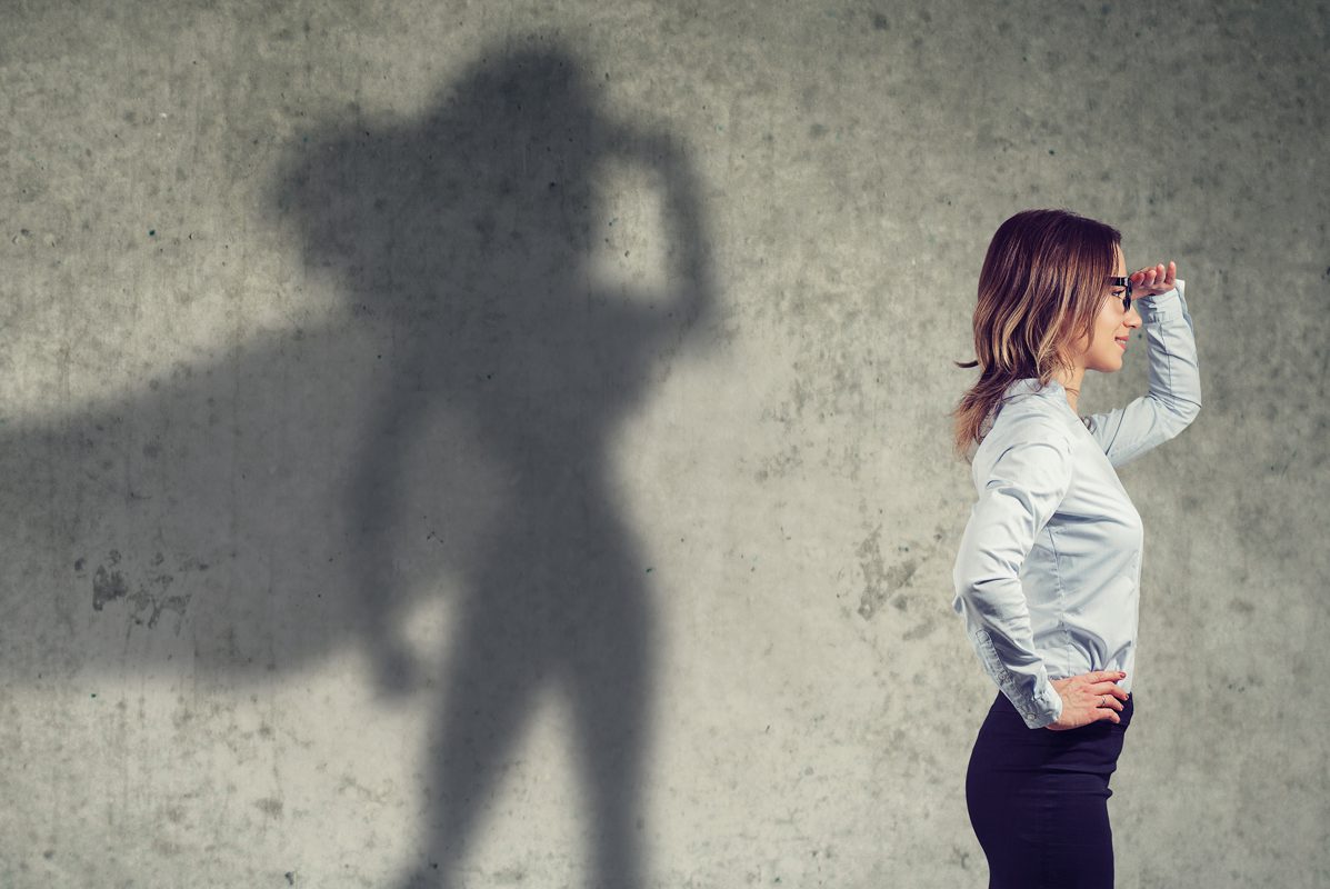 Person with shadow on wall, looking into distance with hand on forehead