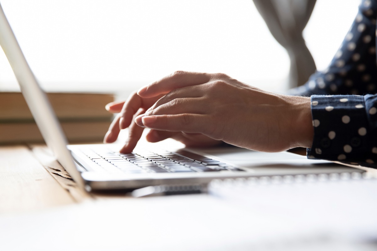 Hands typing on a laptop keyboard with polka dot sleeve visible