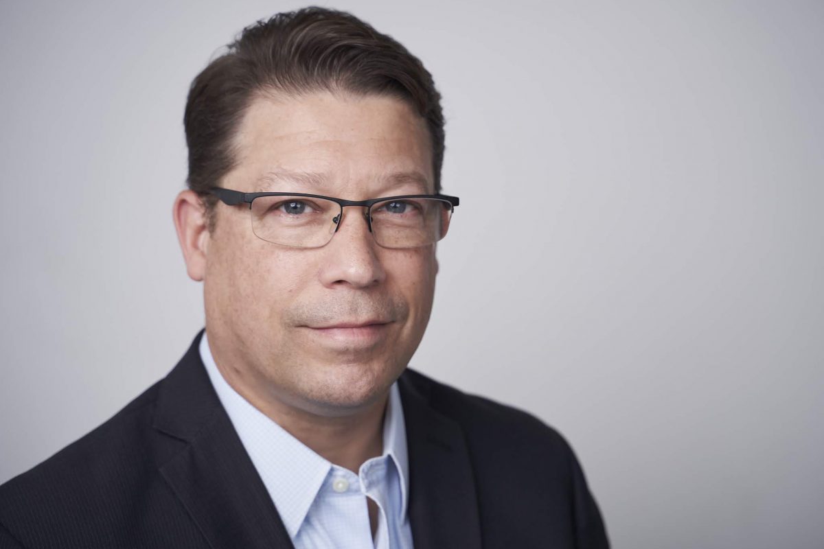 Professional headshot of a middle-aged man in glasses and business attire