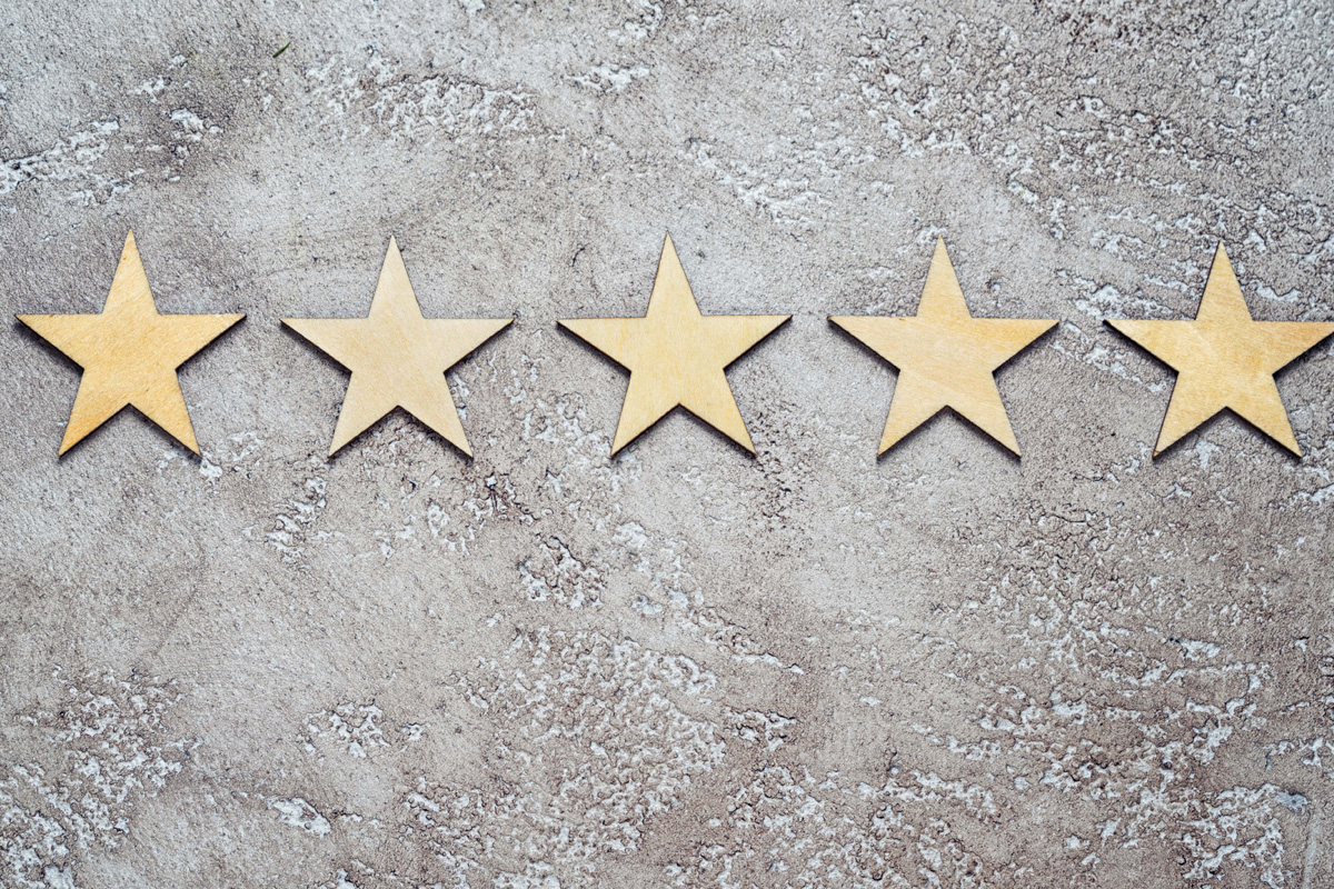 Six wooden stars aligned on a textured gray concrete background