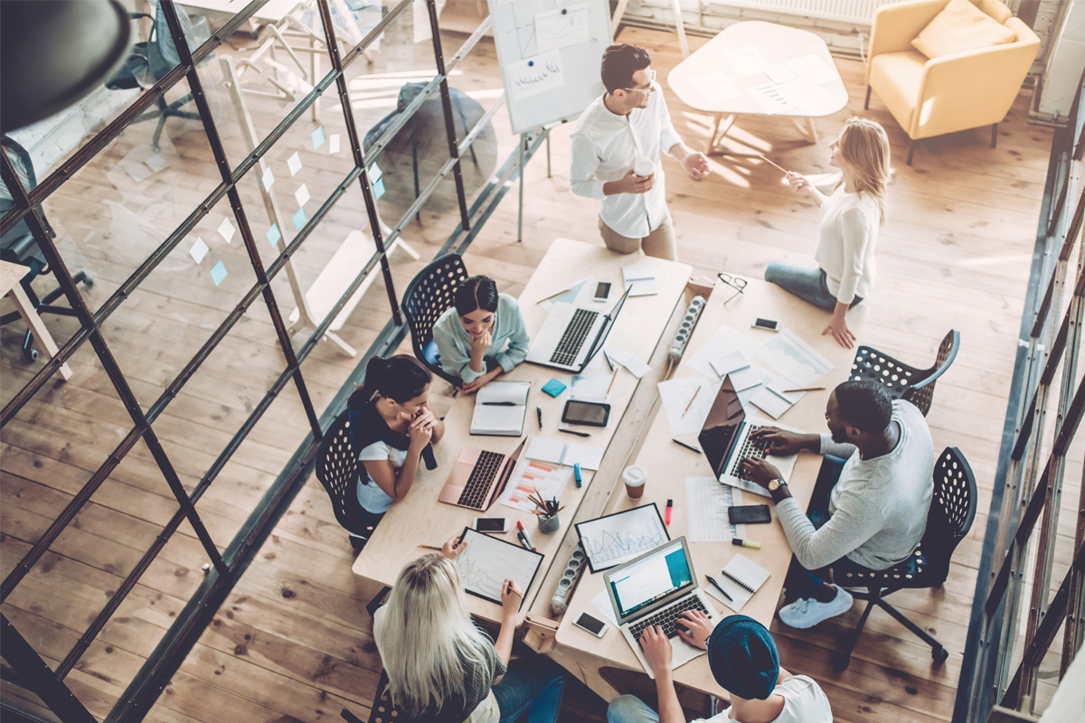 Diverse team collaborating in modern open-plan office with laptops and shared workspace