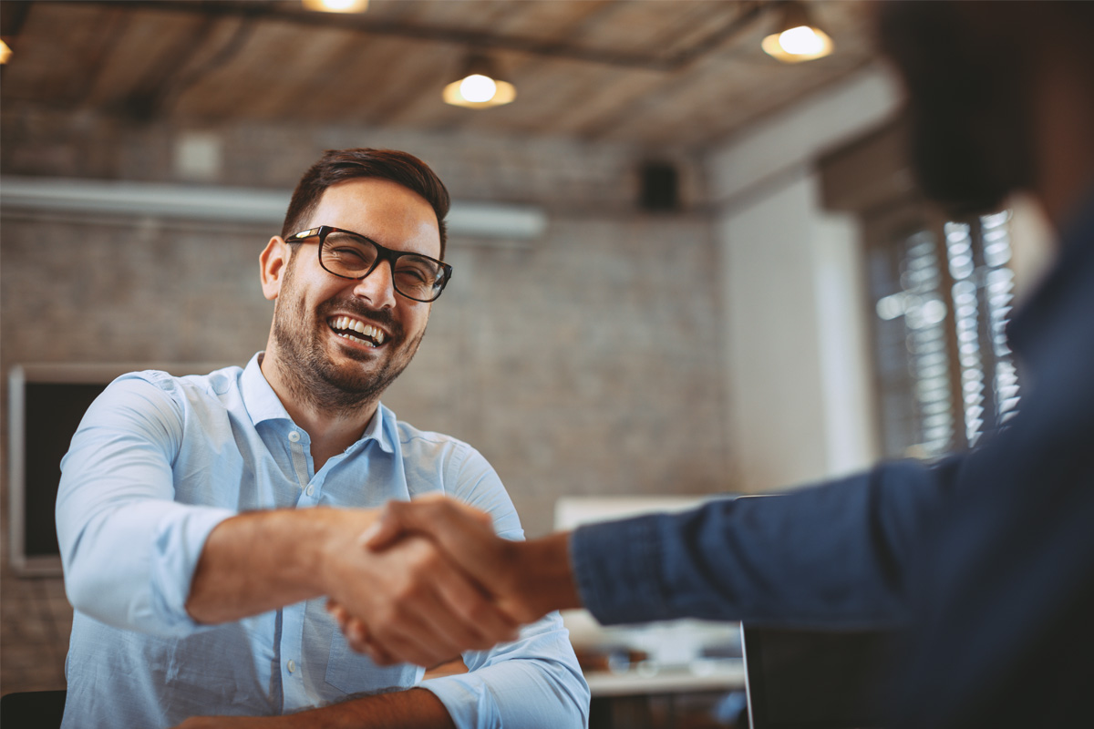 Smiling professional in glasses shaking hands in bright office