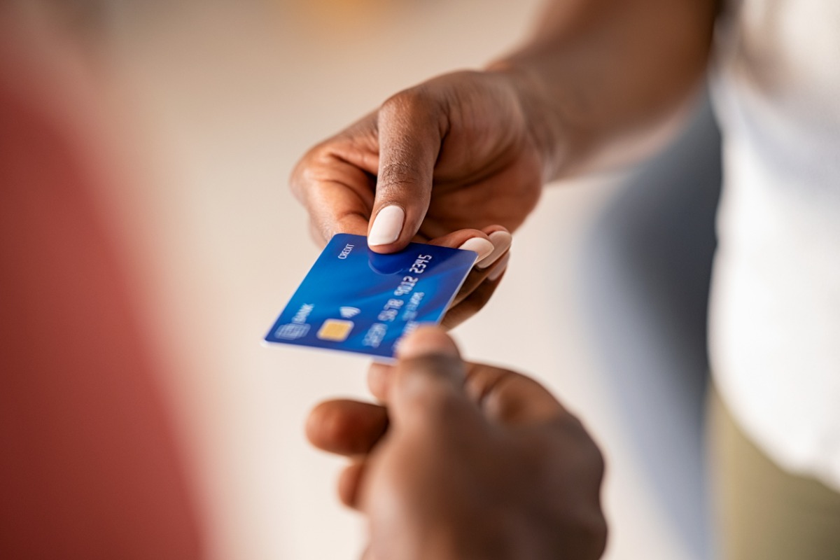 Hand passing blue credit card during payment transaction