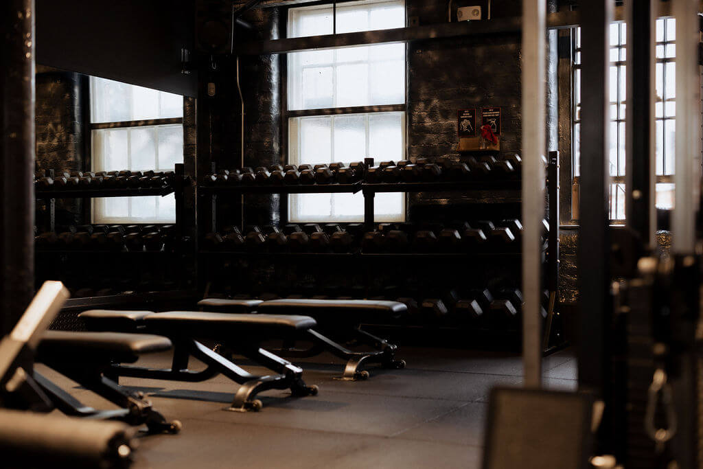Dumbbell racks and benches in the free weights area at ONE|DZ Gym in Derby