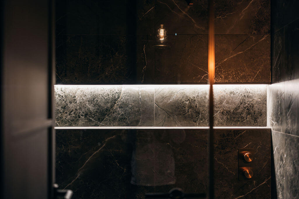 Modern shower area with marble walls at ONE|DZ Gym in Derby