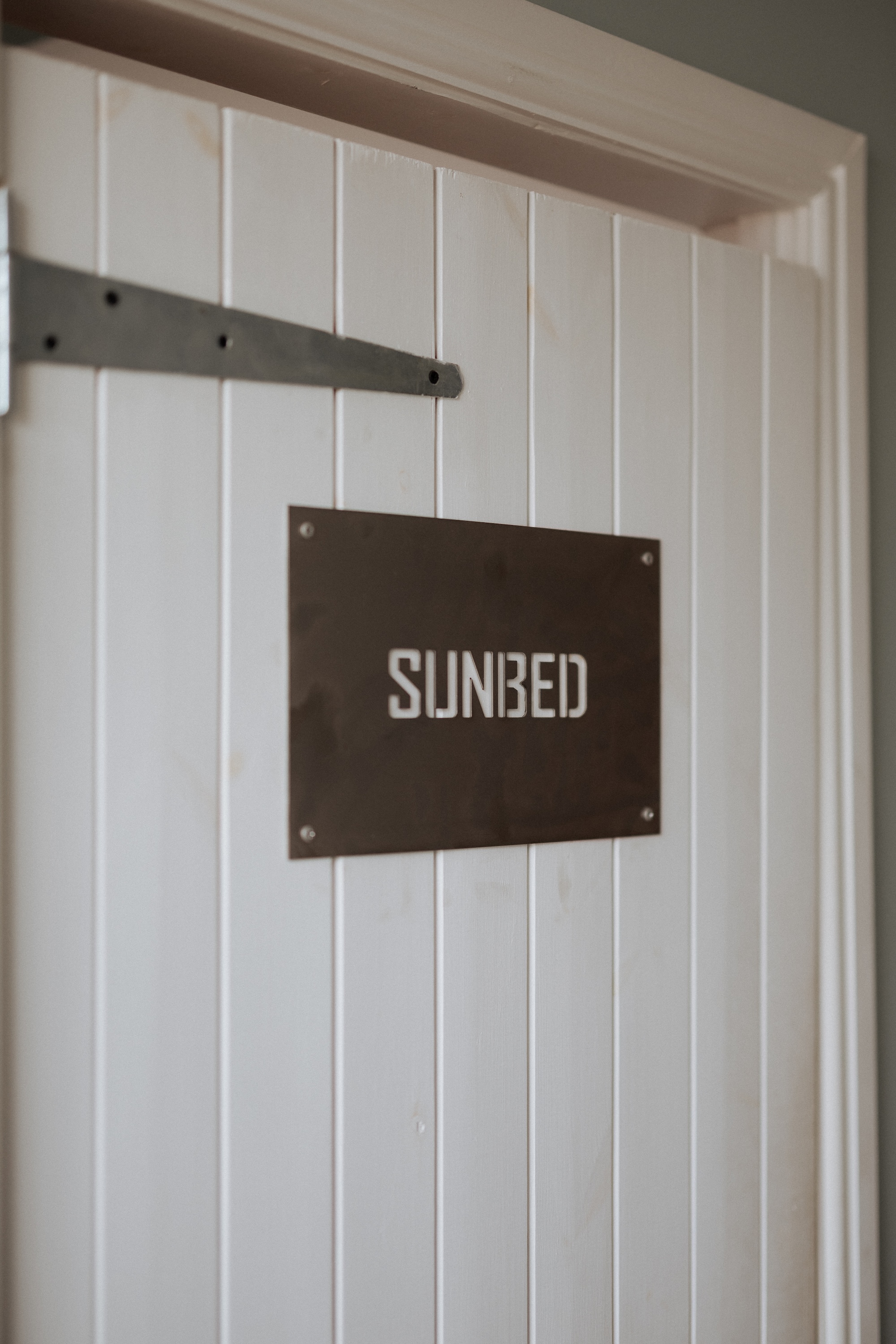 White wooden door with sunbed sign at ONE DZ Gym in Derby