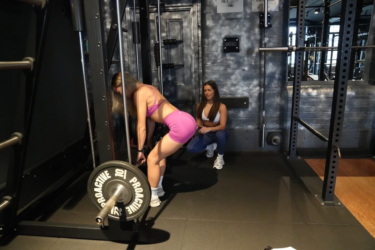 Personal training client doing Smith machine RDLs for glutes with coach at ONE|DZ Gym Derby