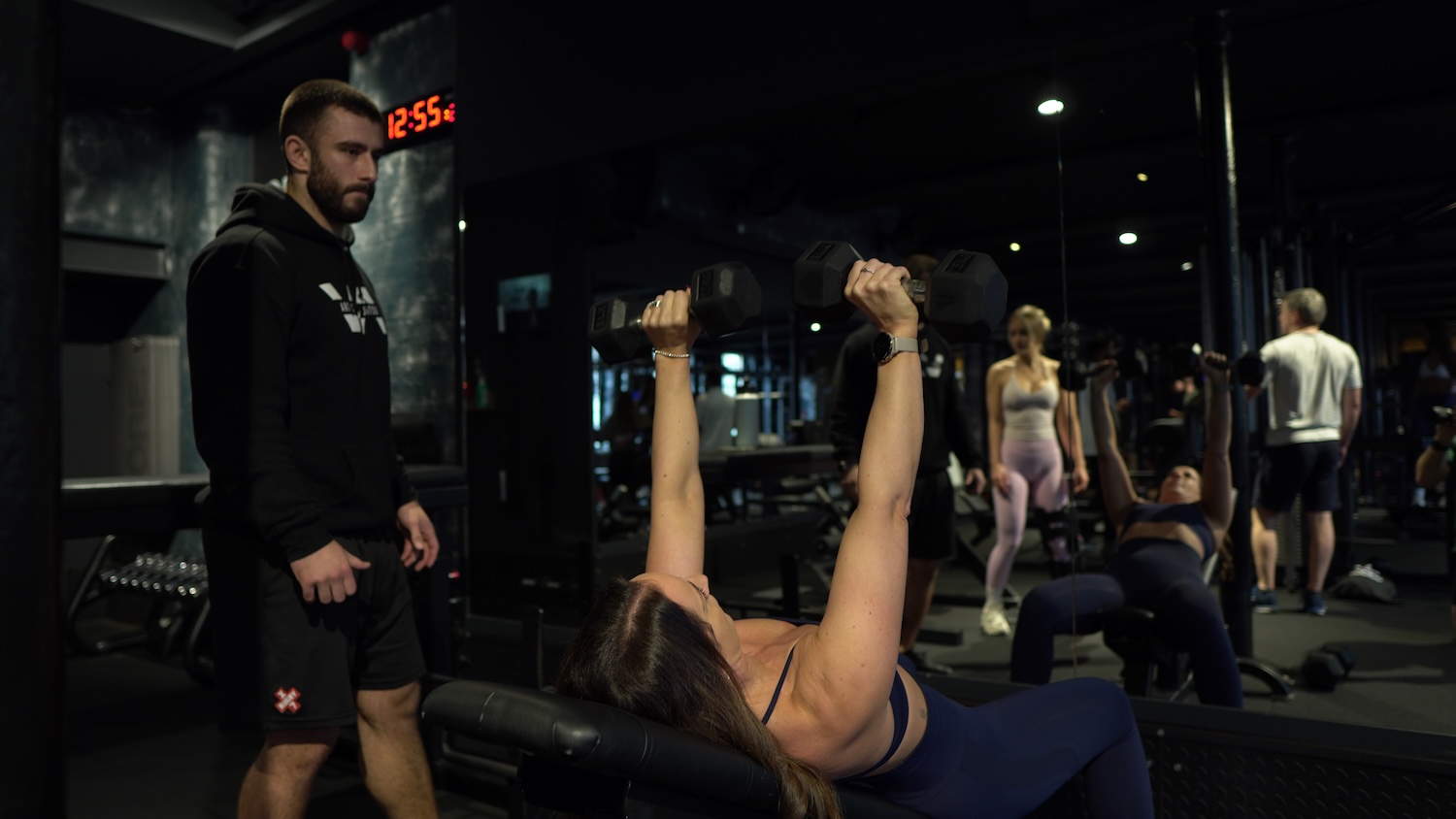 Woman coached through cable bicep curl during PT session at ONE|DZ Gym