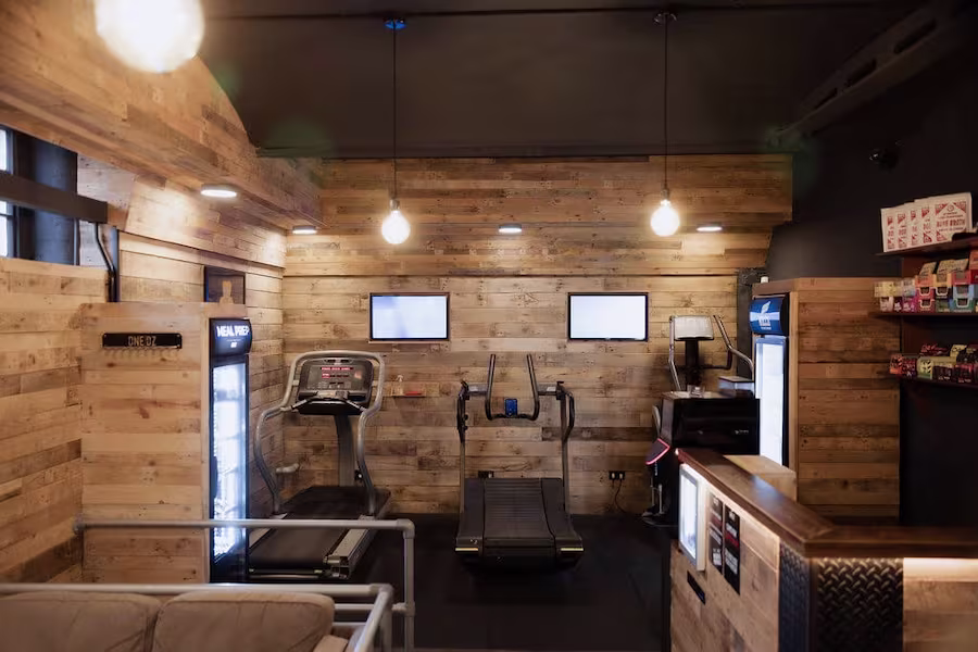 A row of cardio machines such as treadmills and ellipticals in a modern gym.