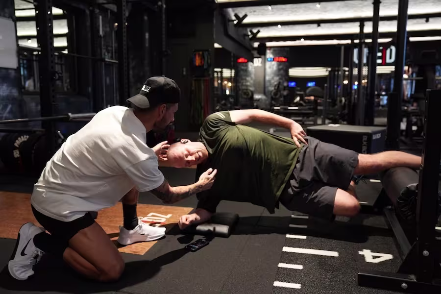 Female personal trainer coaching client during a seated bench session at ONE|DZ Gym
