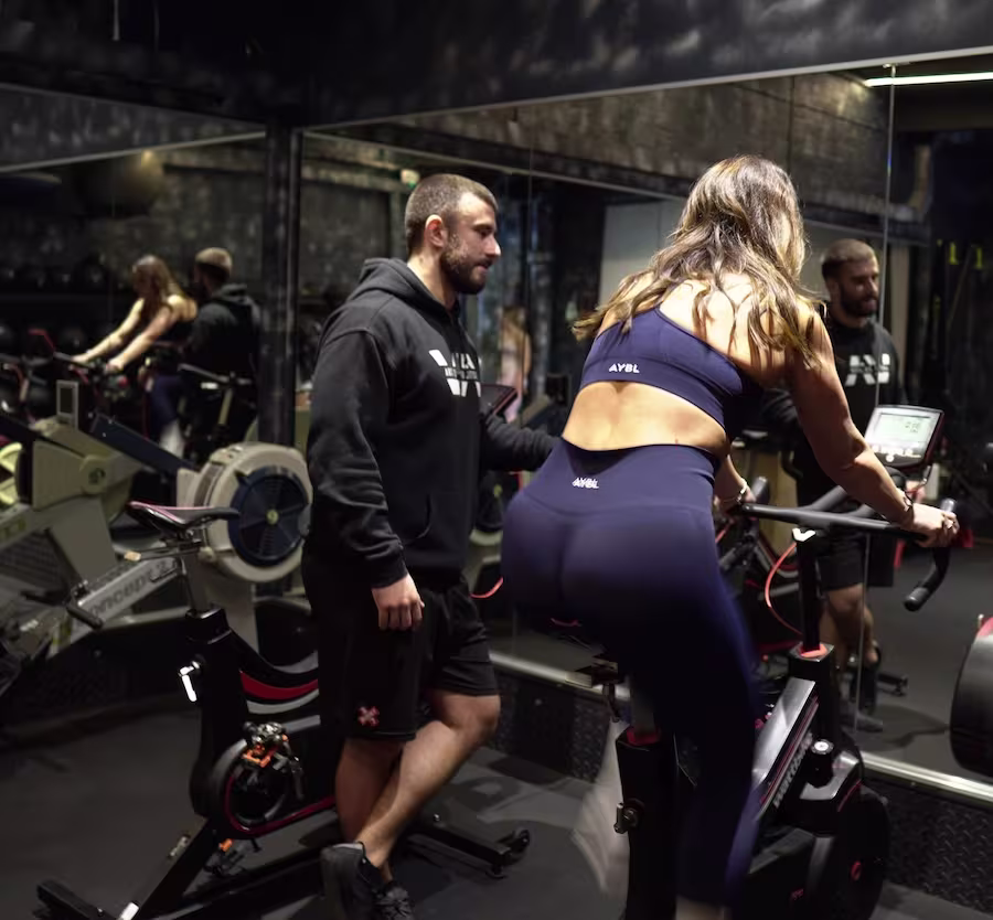 Female client on assault bike during personal training conditioning session at ONE|DZ Gym