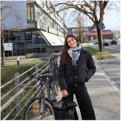 Молода жінка в зимовому одязі стоїть на тротуарі біля велосипедів у сучасному європейському місті