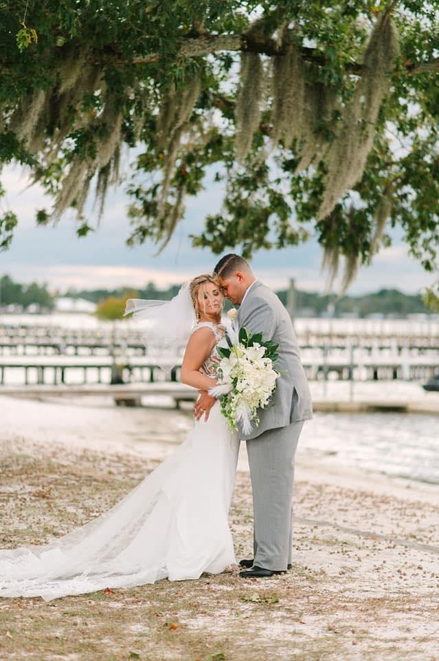 Wedding couple embracing under Spanish moss tree near waterfront dock