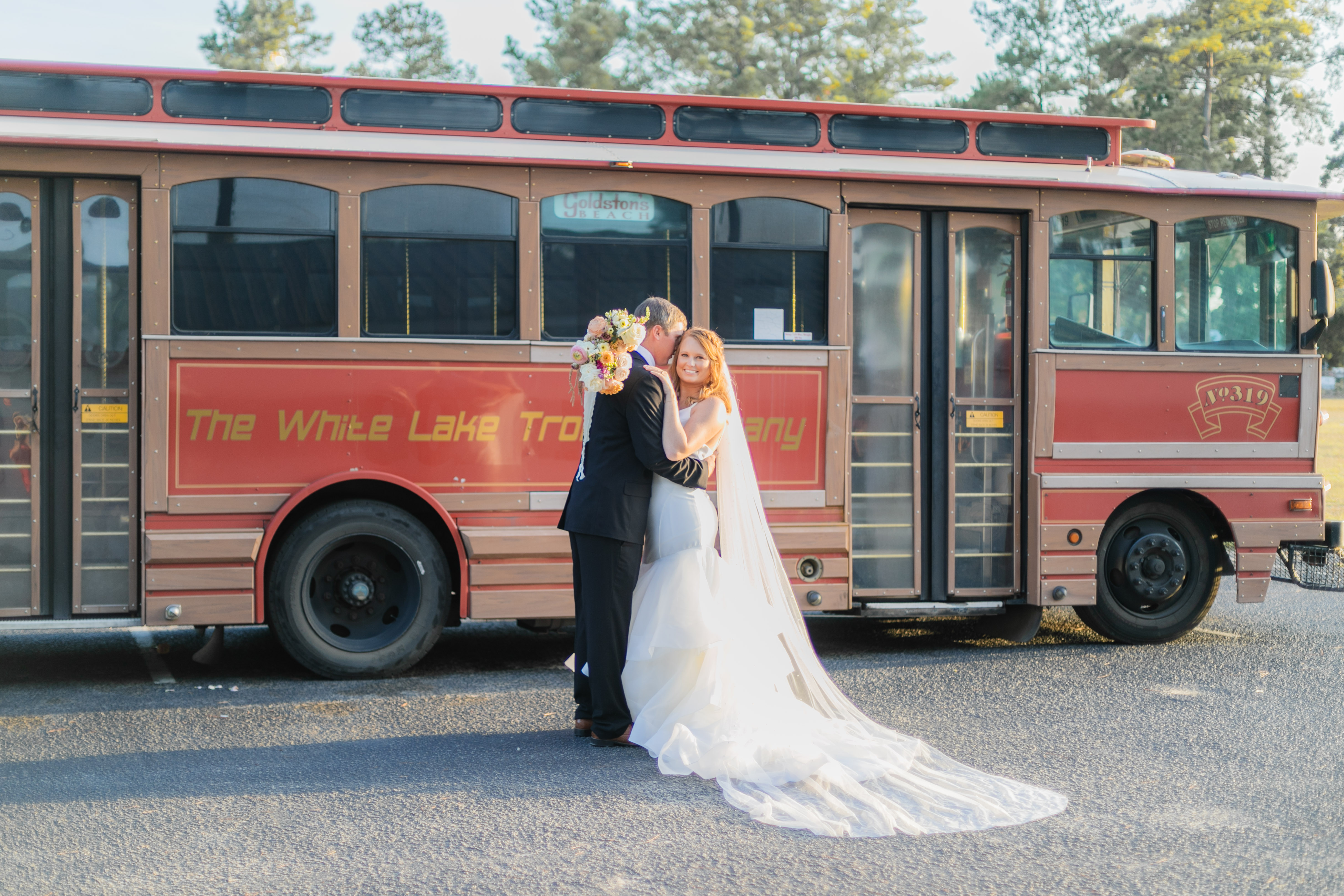 Wedding couple kissing in front of vintage red White Lake Trolley