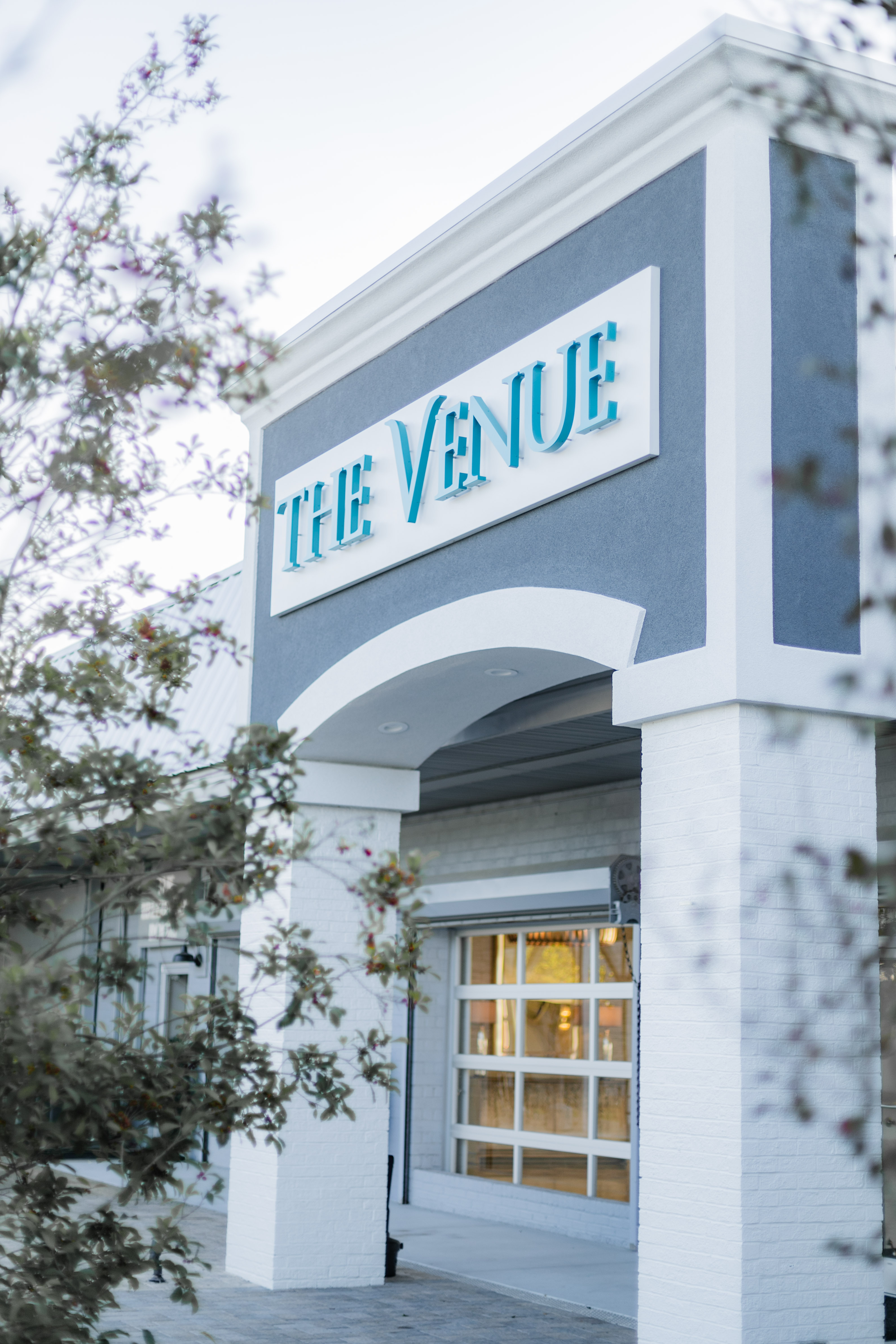 The Venue sign on white and blue building with glass door