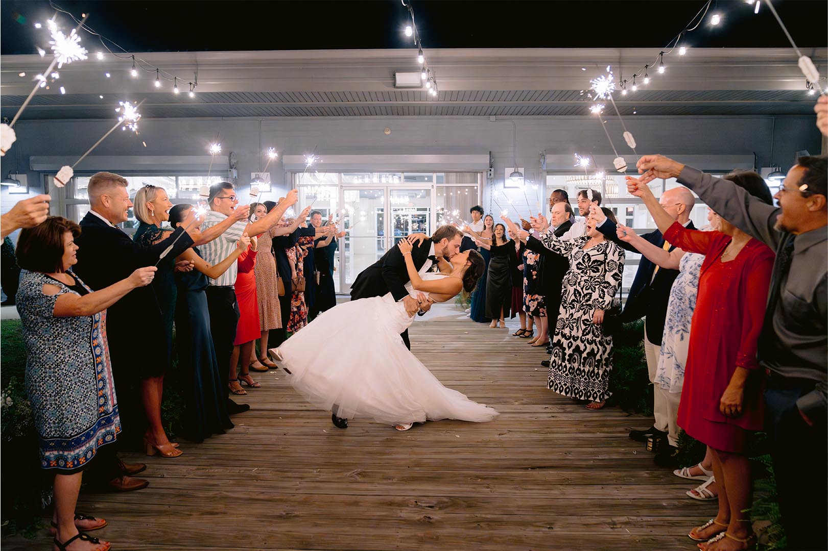 Wedding couple shares first kiss under sparklers with guests cheering