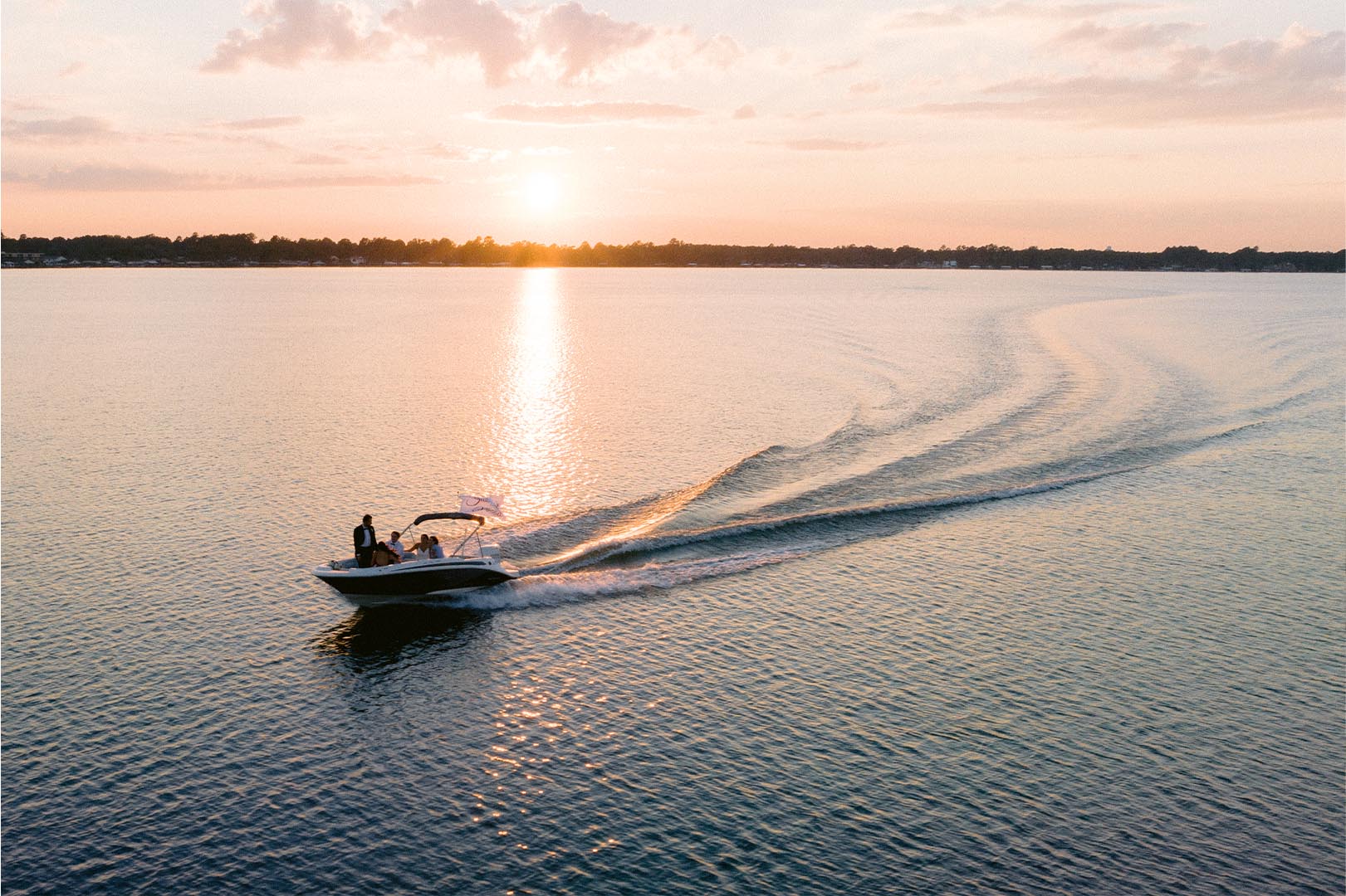 Boat cruising on calm lake during golden sunset with rippling water