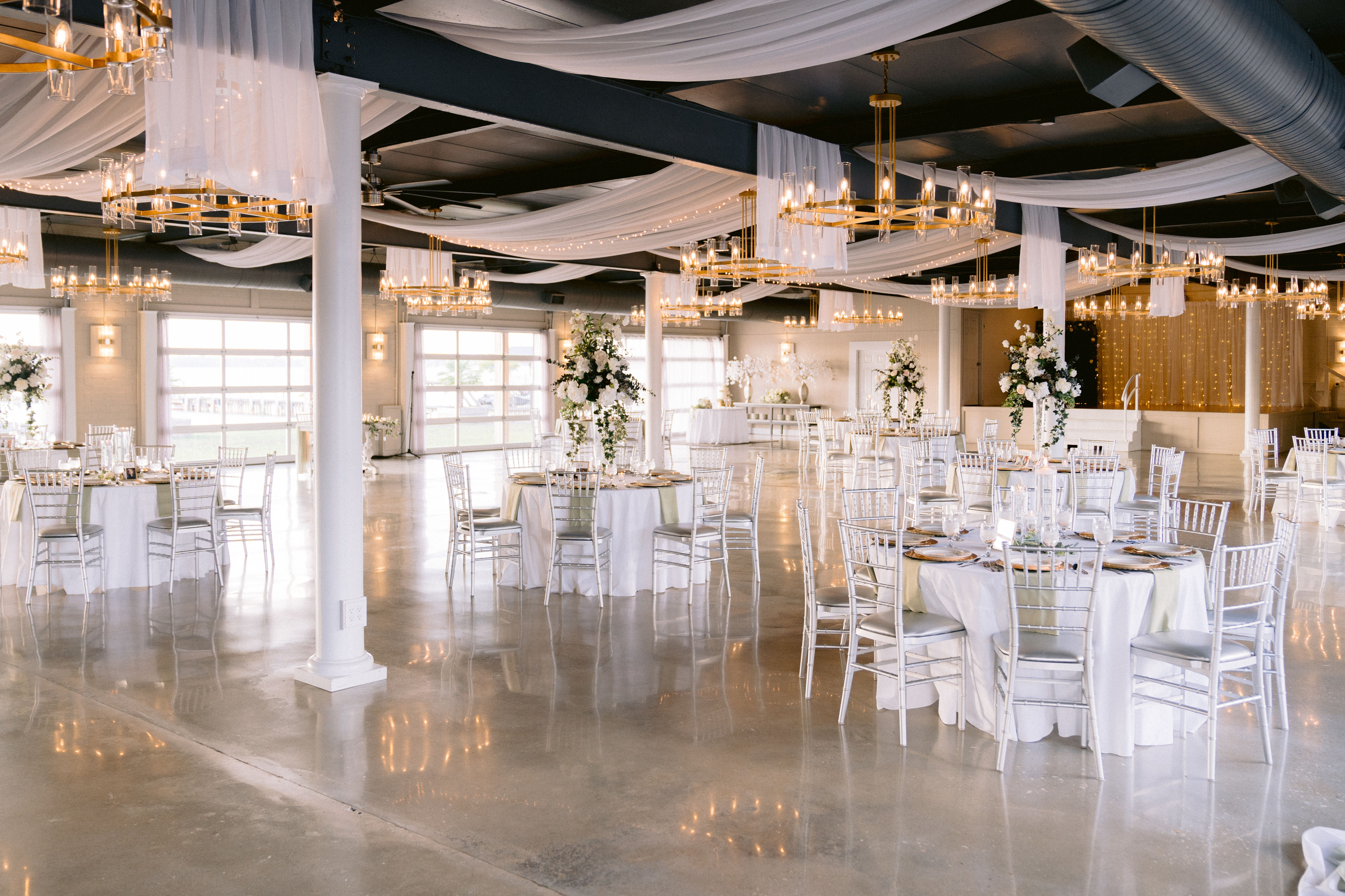 Elegant white wedding venue with chandeliers and decorated tables