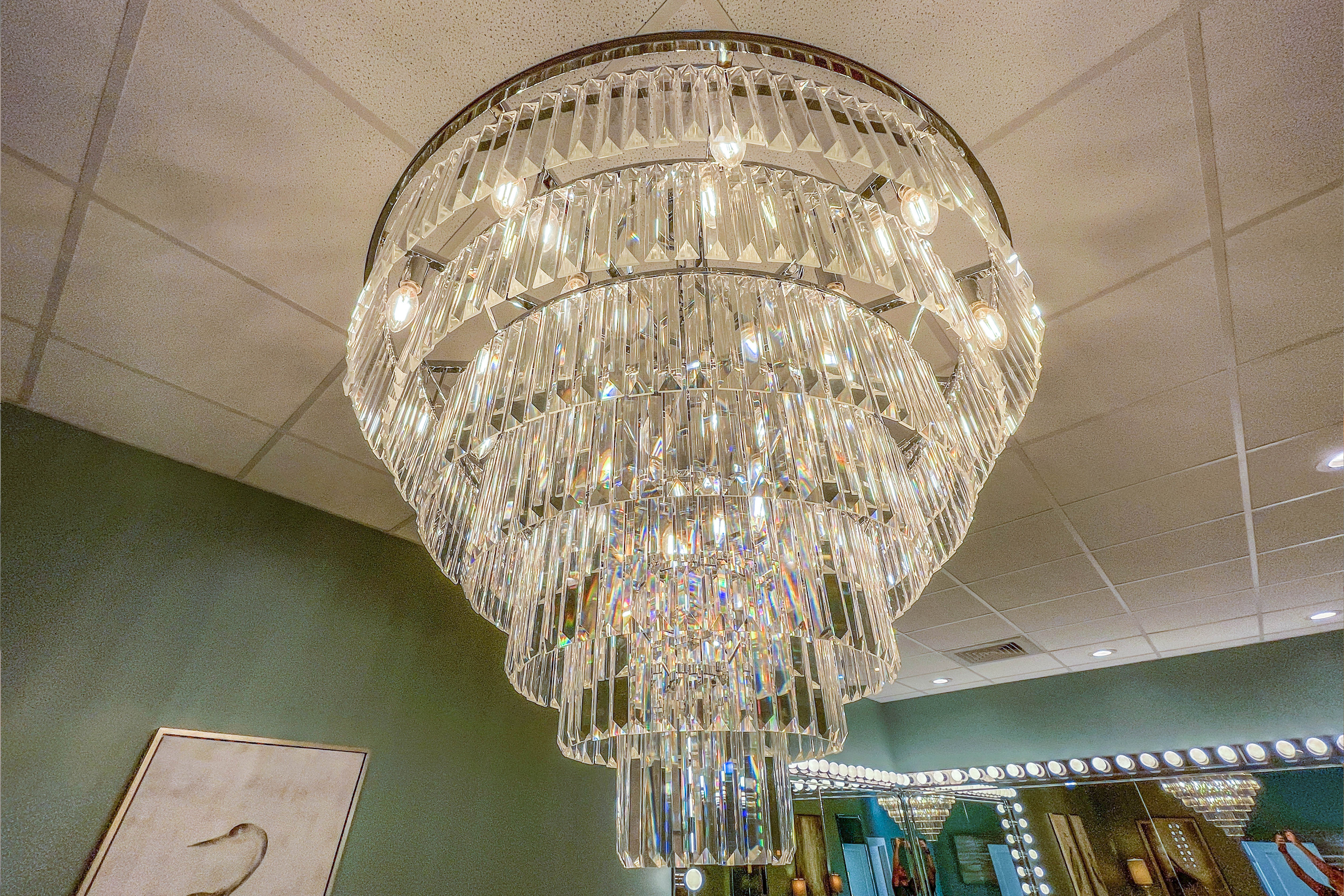 Elegant multi-tiered crystal chandelier hanging from green-walled ceiling