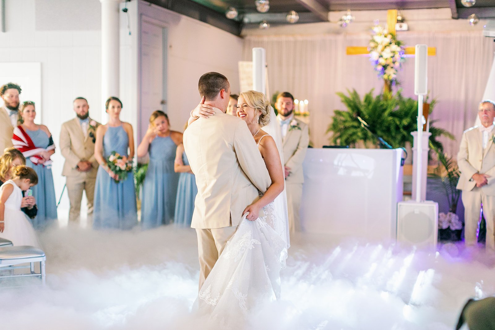 Wedding couple dancing on misty dance floor surrounded by wedding party