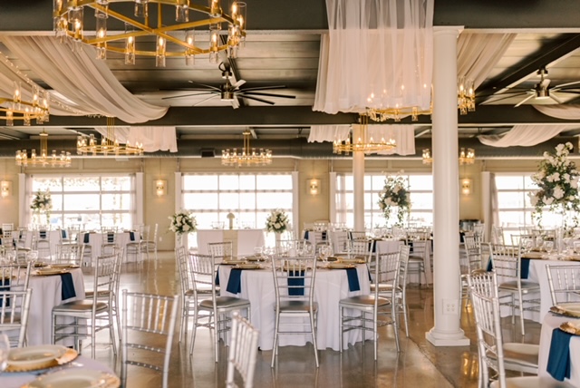 Elegant wedding venue with white drapes, chandeliers, and blue accented tables