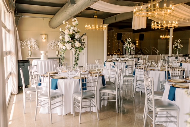 Elegant wedding reception with white tables, chairs, and floral centerpieces