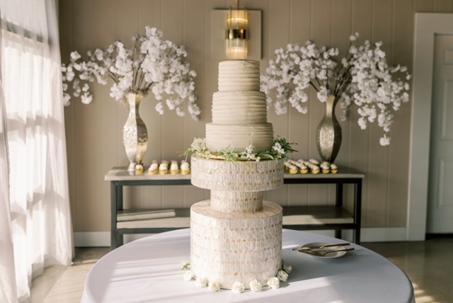 Elegant white wedding cake on textured stand with floral decorations