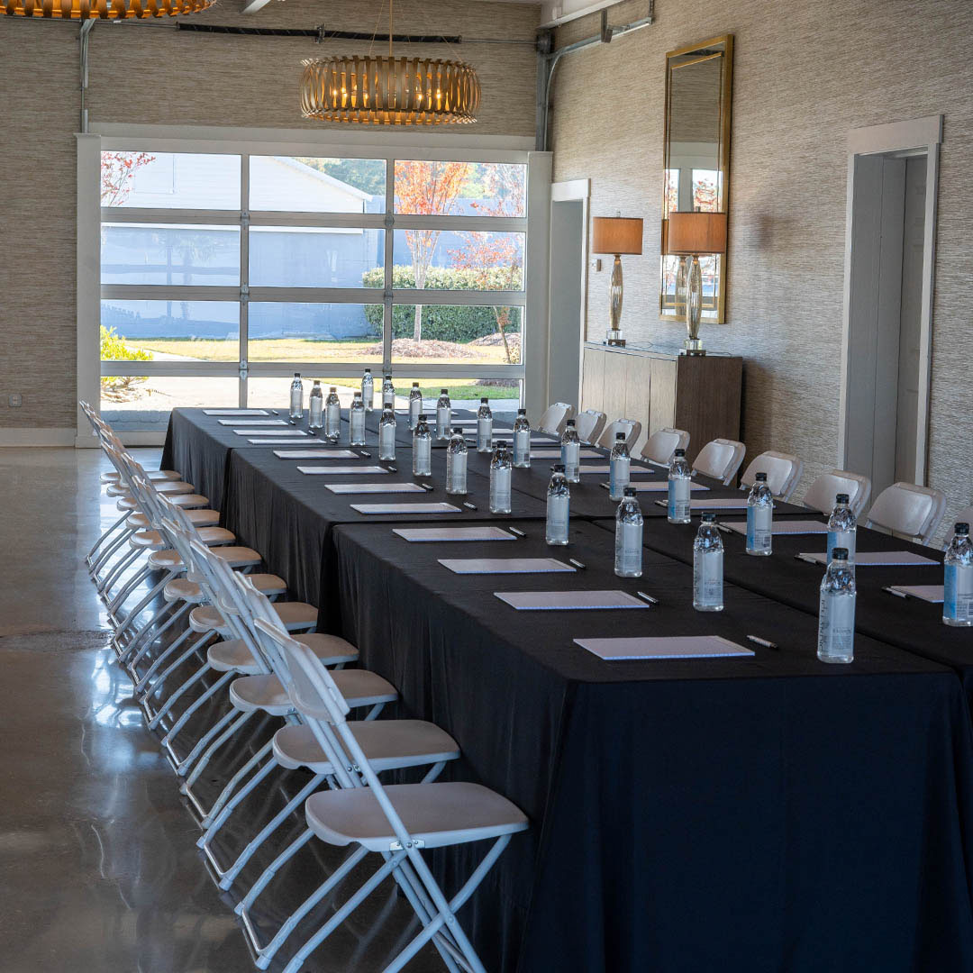 Modern conference room with long black table, white chairs, and autumn view