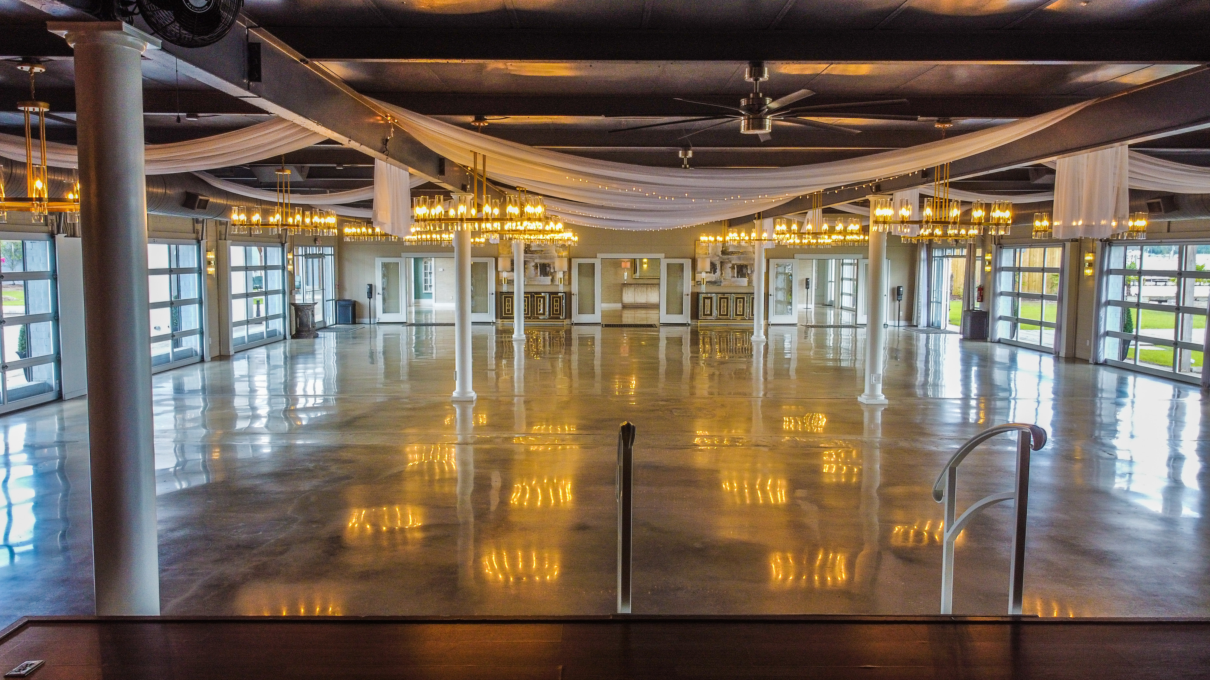 Elegant event venue with chandeliers, draped ceiling, and reflective polished floor