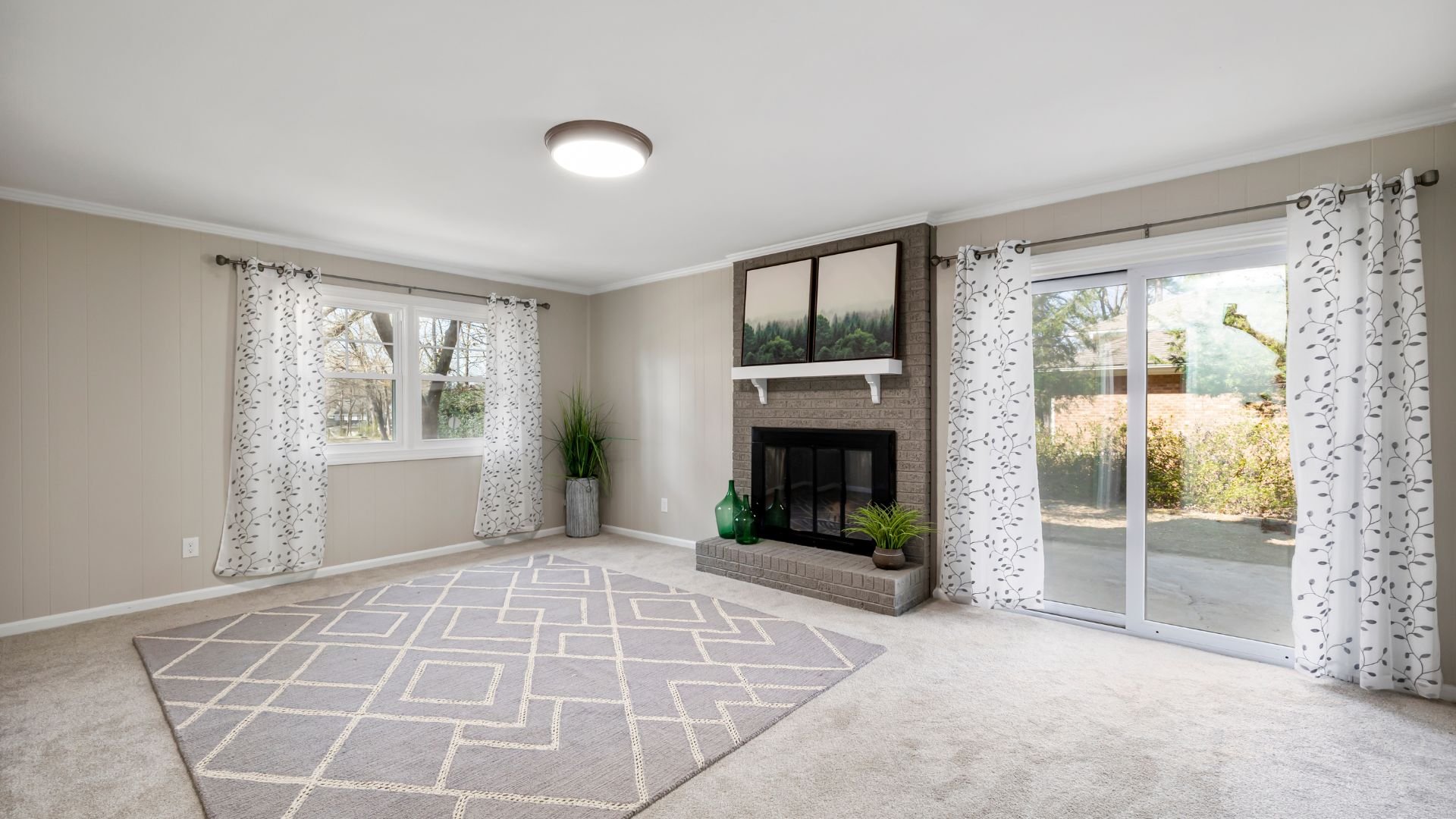 Bright living room with fireplace, large windows, and geometric area rug