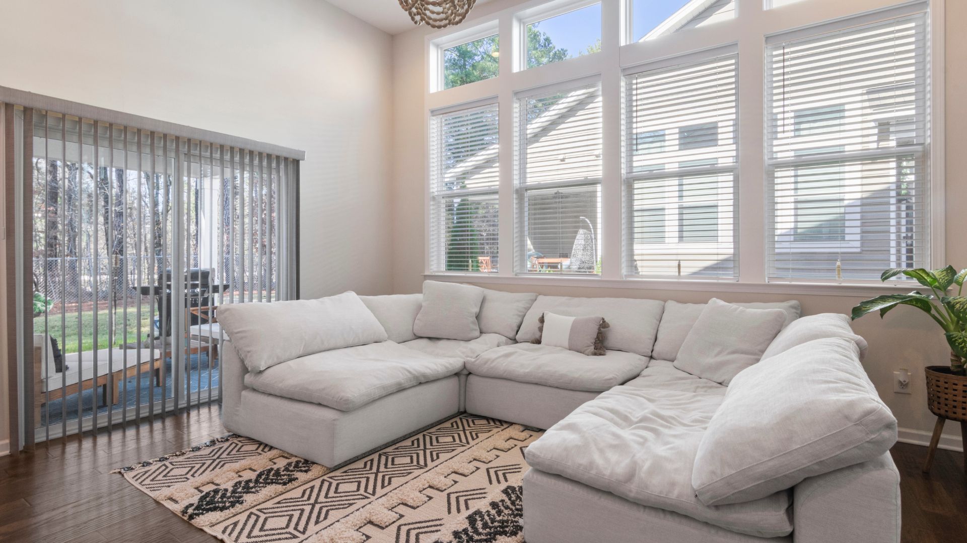 Bright living room with white sectional sofa, large windows, and patterned rug