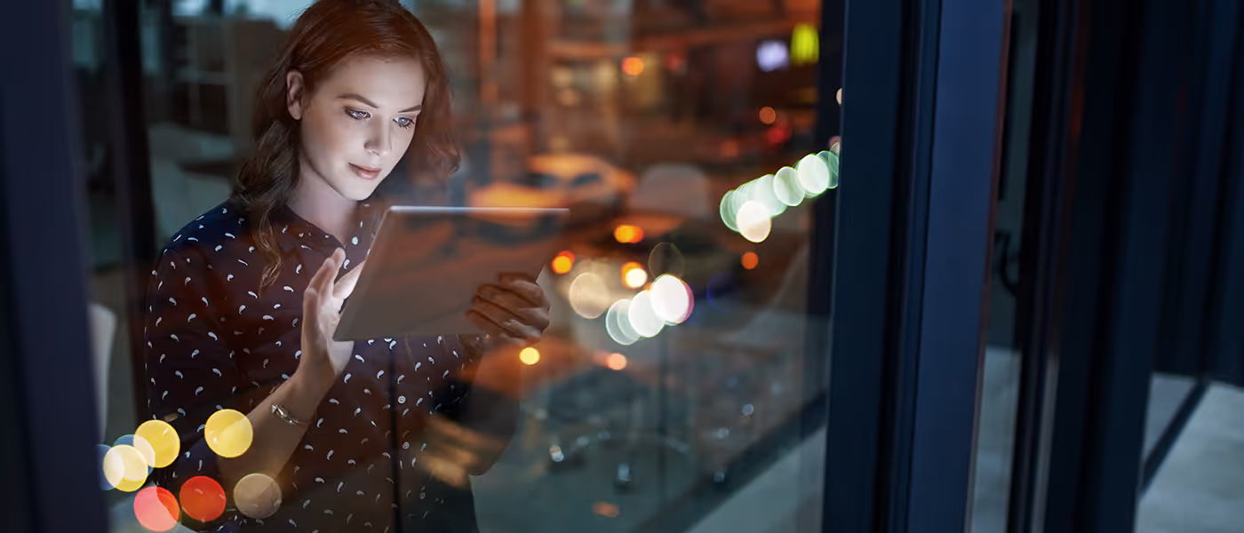 Woman working on a tablet close to the building window