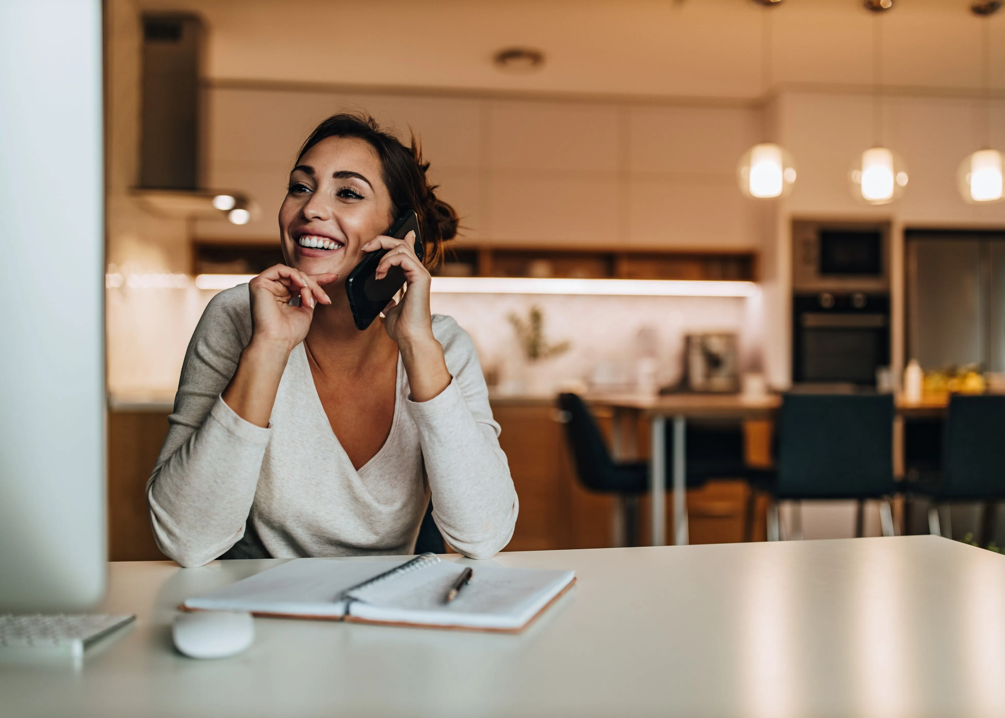 A woman sitting at a table talking on a cell phone.