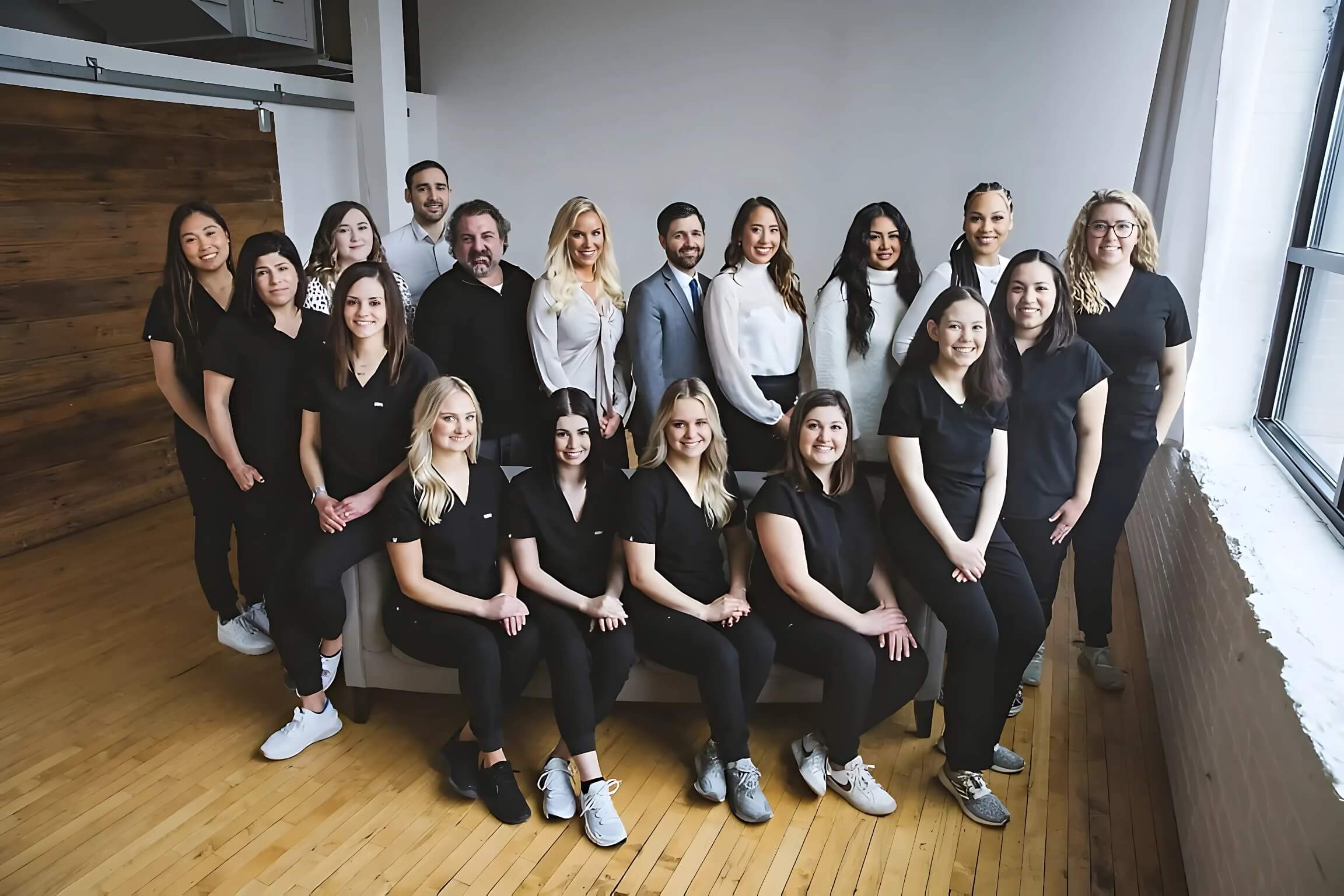 Full Loop Dental team photo with staff and dentists smiling together in a bright, modern clinic space with hardwood floors and soft natural light
