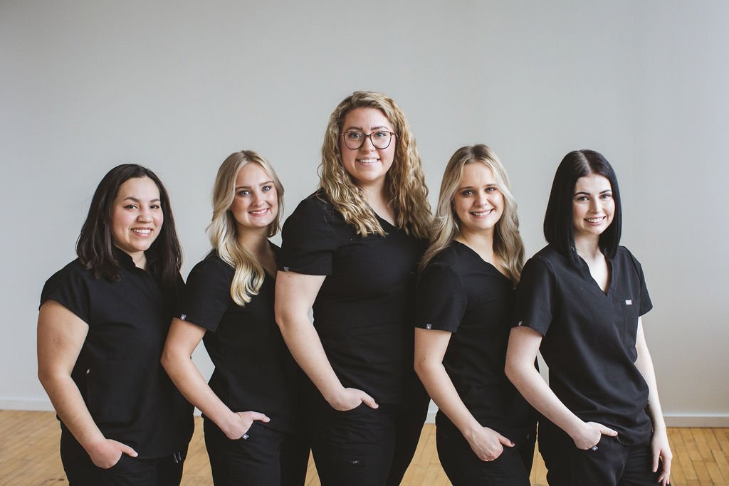 Loop Dental’s hygienist team standing side by side in black uniforms, smiling confidently against a neutral office backdrop