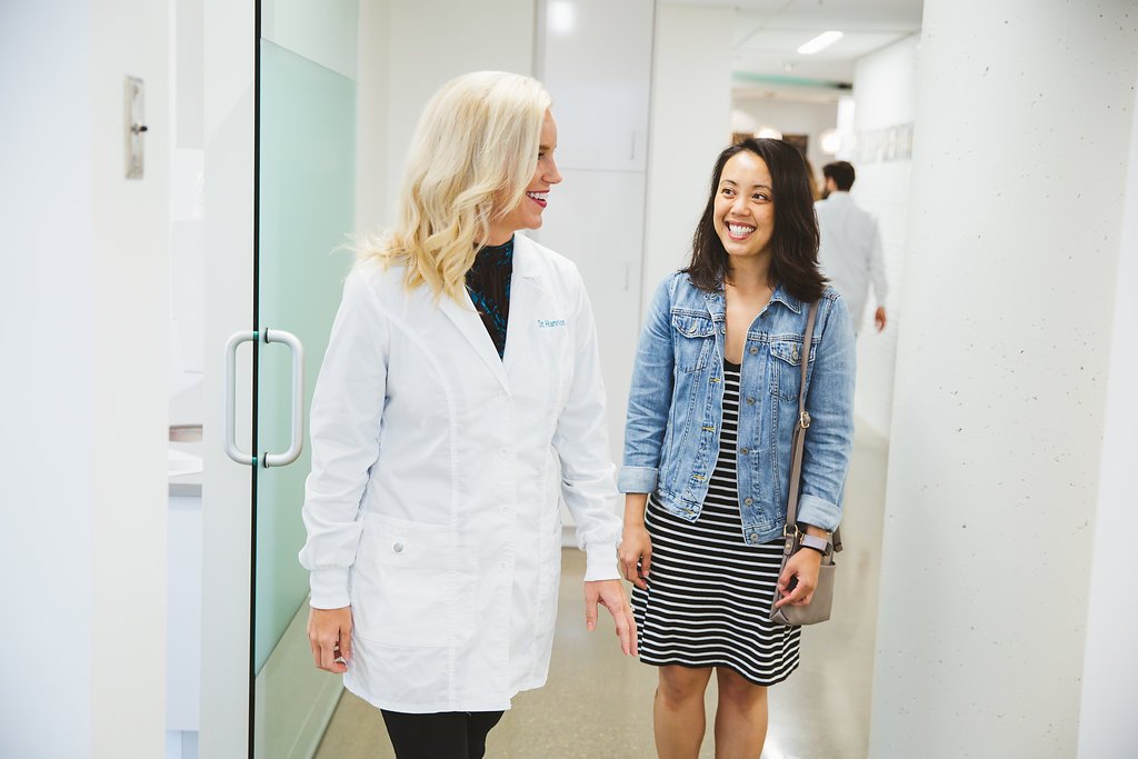 Dr. Katie Hannon walking alongside a patient in a bright hallway at Loop Dental, both smiling during a friendly conversation