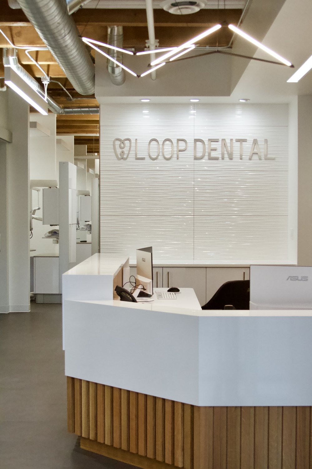 Reception area at Loop Dental featuring a modern white desk, a team member behind the counter, and a well-lit space designed for patient check-in