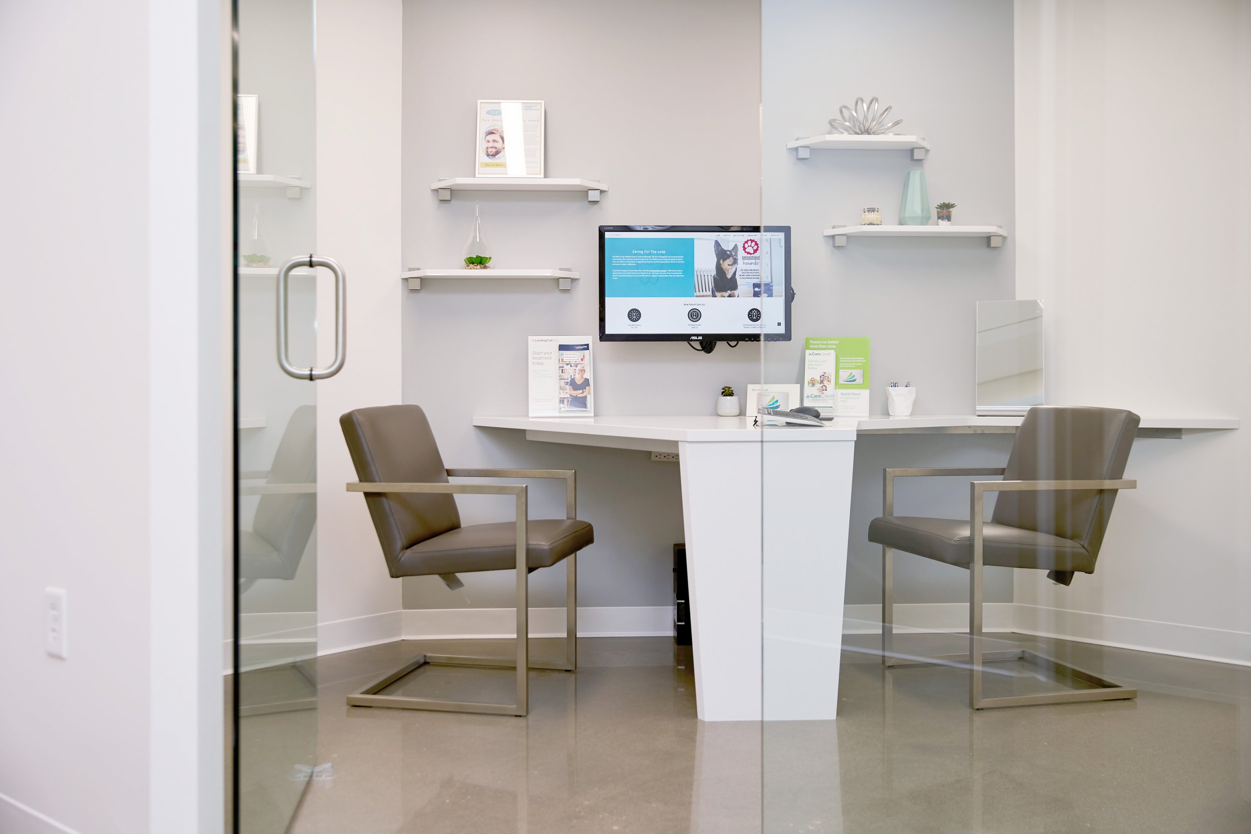 Modern dental operatory setup at Loop Dental featuring two treatment chairs and mounted monitors in a clean, bright room